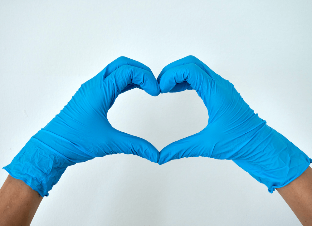 nurse with nitrile gloves on doing a heart sign